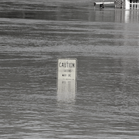 black and white photo of a speed limit sign submerged in water